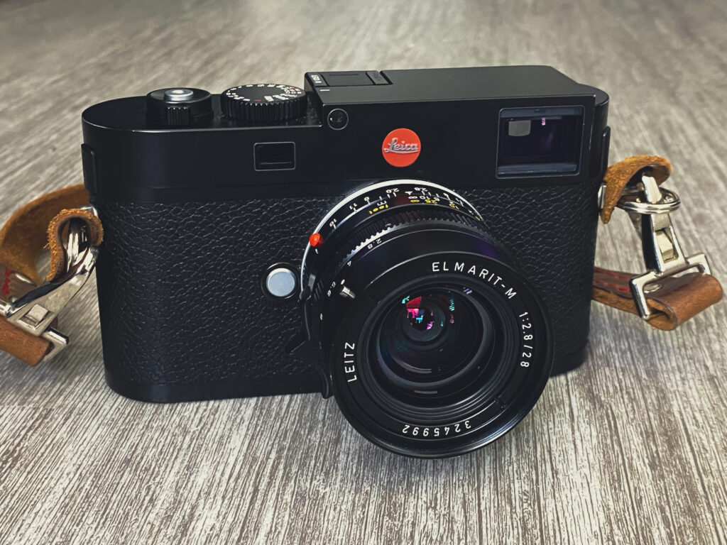Black Leica M camera with a Leitz Elmarit lens on a wooden surface