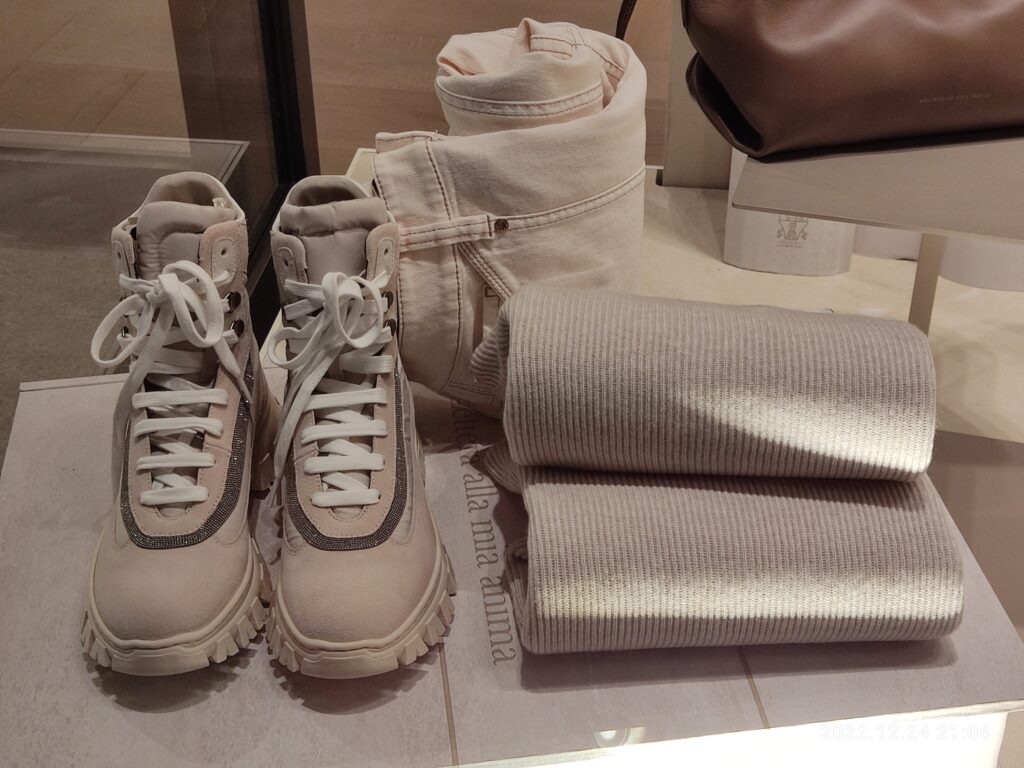 Folded knitwear, trousers, shoes and a leather bag in a Brunello Cucinelli display