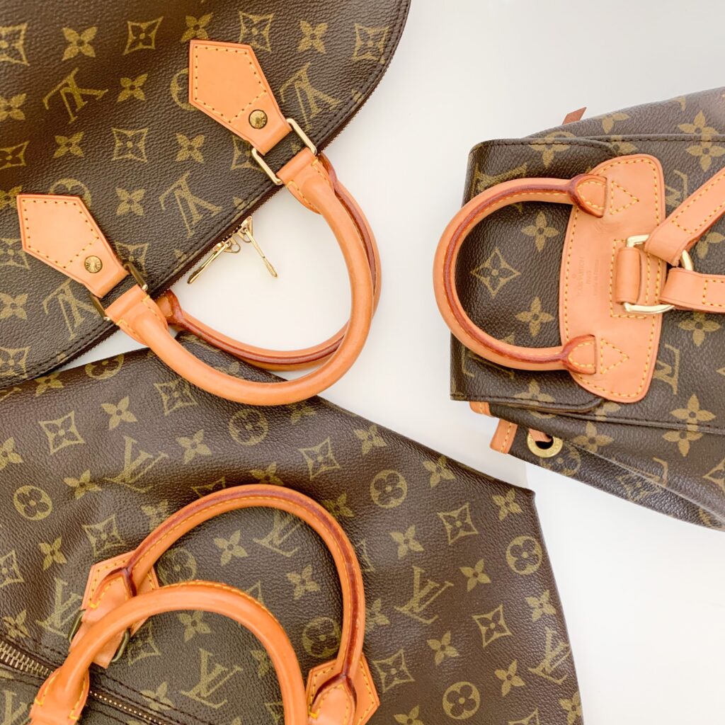 Louis Vuitton Monogram bags with pale leather handles arranged on a light surface