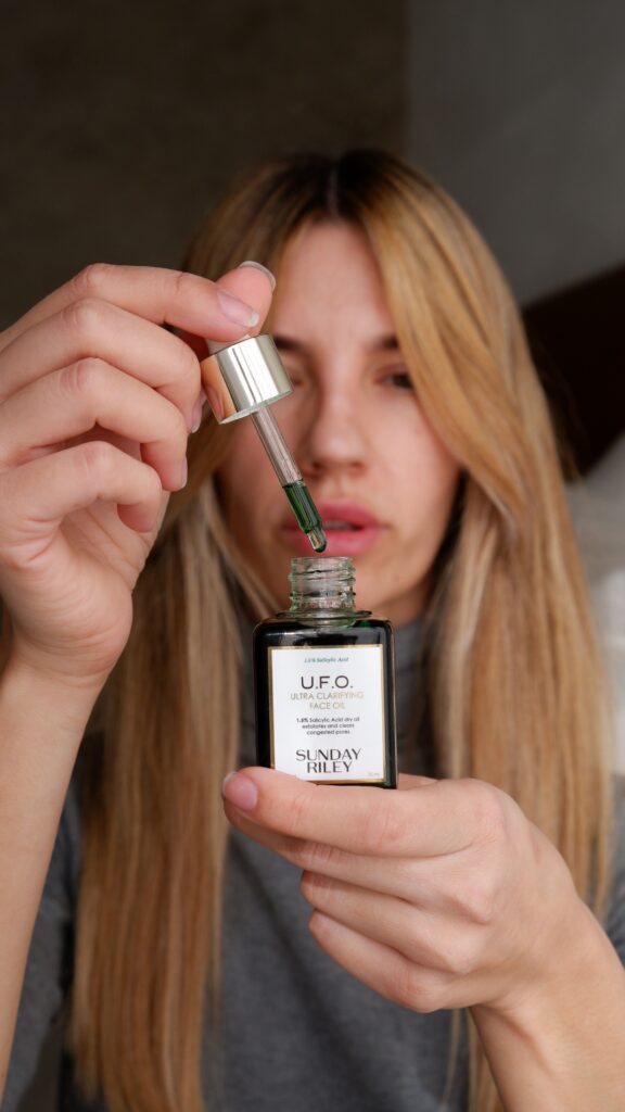 Close-up of a Sunday Riley U.F.O. treatment-oil bottle held in a hand
