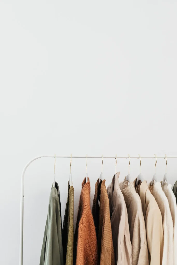 Clothing in neutral tones hanging on a rail
