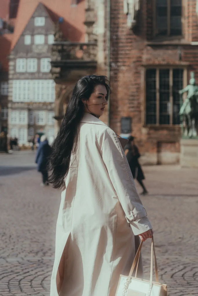 A woman wearing a trench coat on a city street