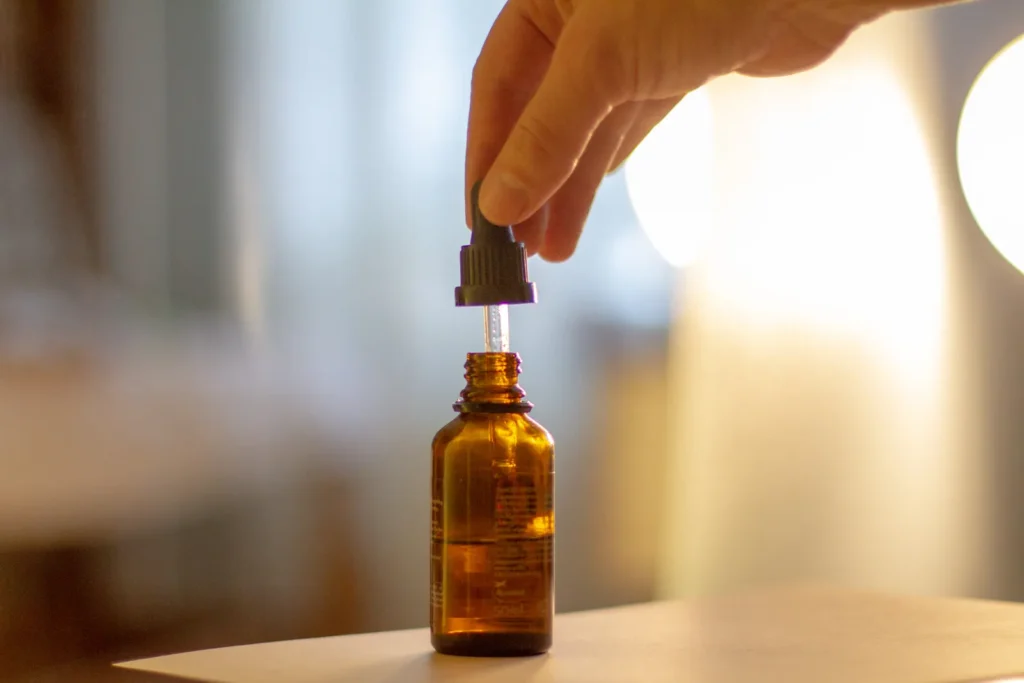 A hand holding a small dropper bottle