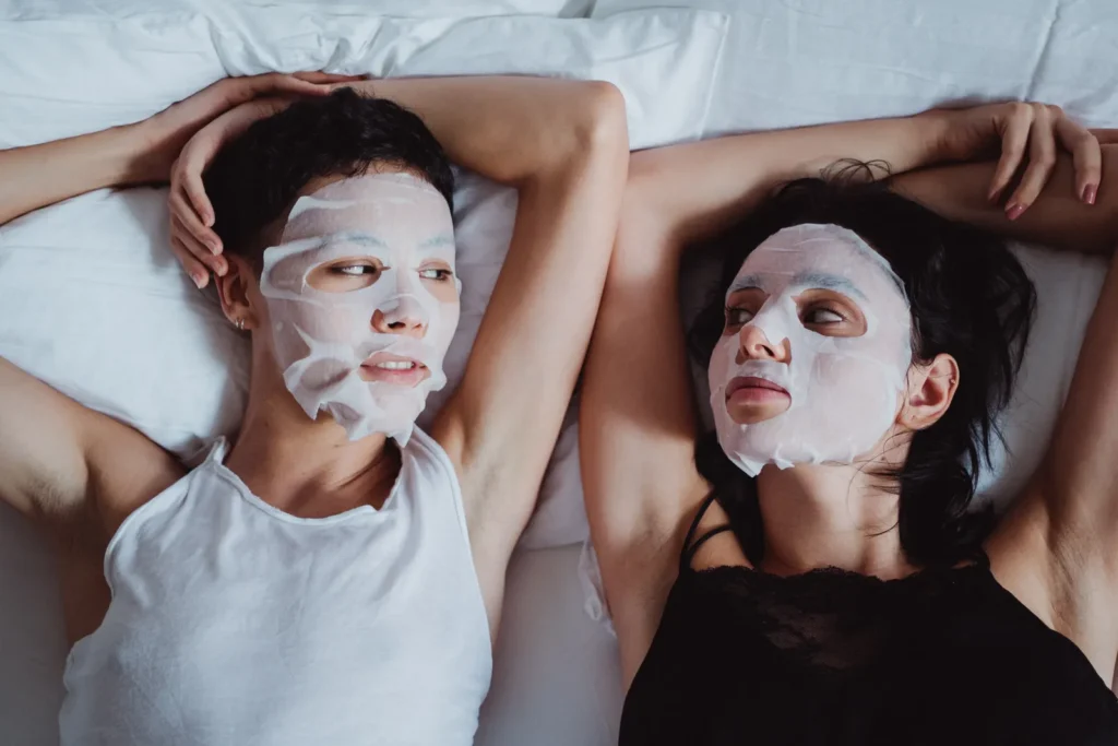 Two people wearing facial sheet masks indoors