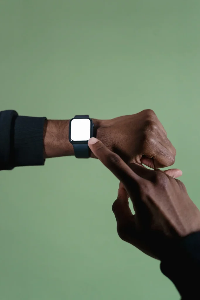 A hand pointing to a smartwatch worn on the wrist