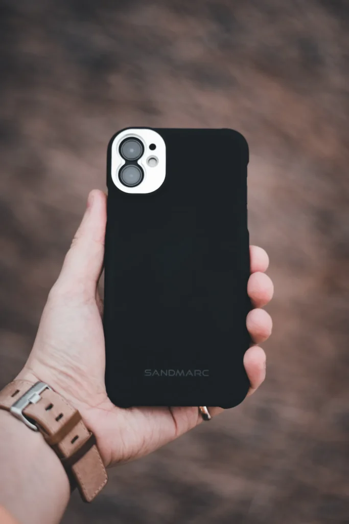 A hand holding a smartphone fitted with a dark case