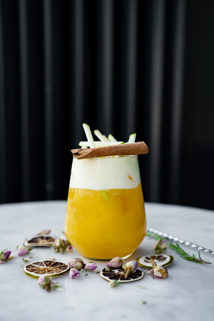 A citrus drink with an apple and cinnamon garnish