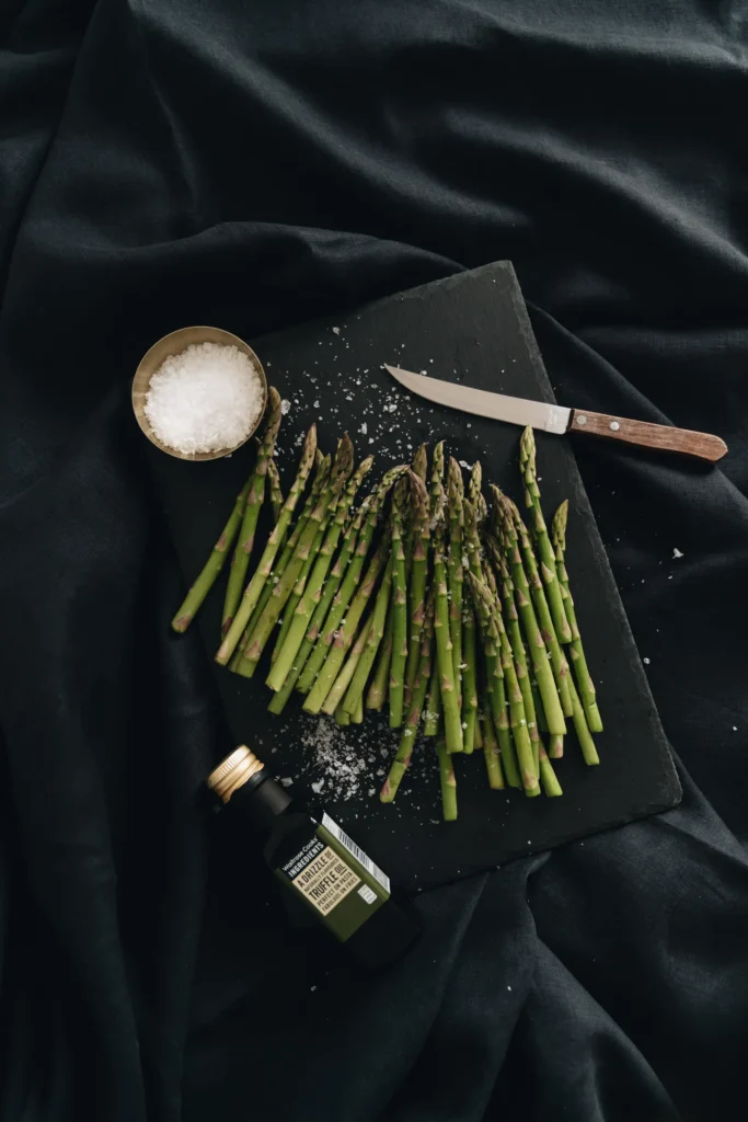 Asparagus, truffle-flavoured oil and salt on a dark surface
