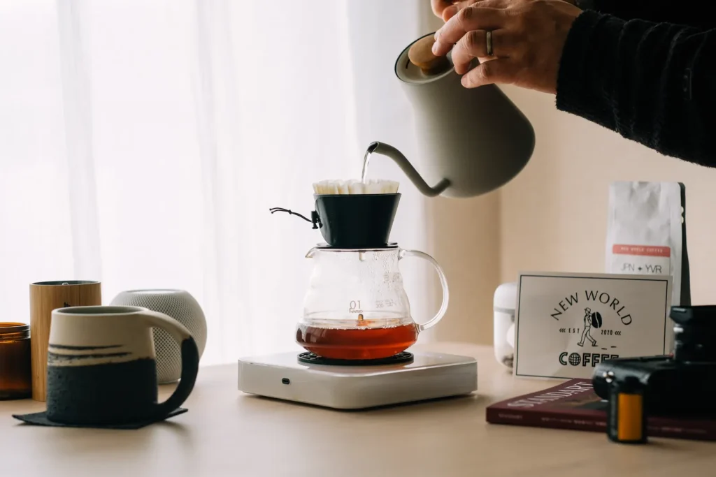 A hand pouring water into a filter-coffee brewer