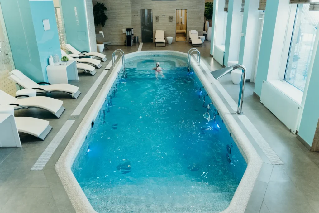 An indoor spa pool with lounge chairs and a swimmer