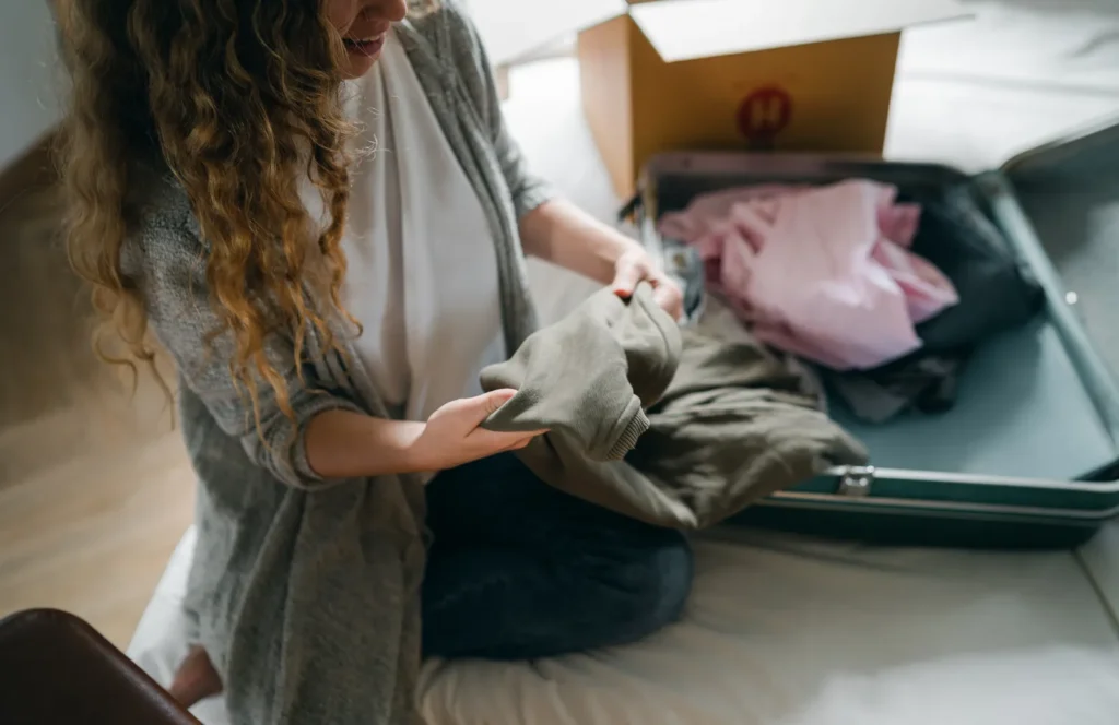A person packing clothes into an open suitcase