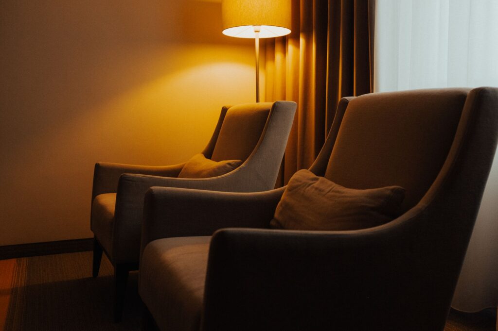 Two upholstered armchairs beside a softly glowing floor lamp.